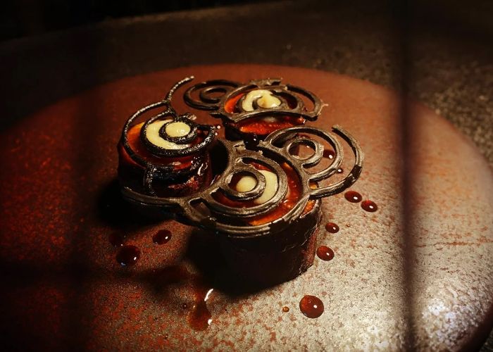 A fancy dessert at Alternative, featuring delicately shaped chocolate in a spiral pattern.