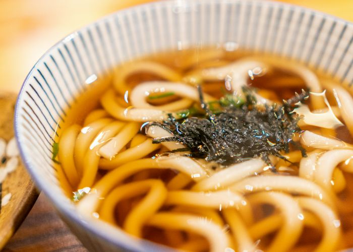 Udon noodles in a dark broth, garnished with seaweed,
