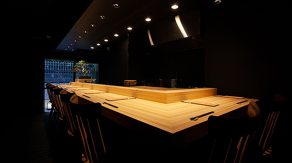 Elegant dark-themed restaurant interior with minimalist wooden seating