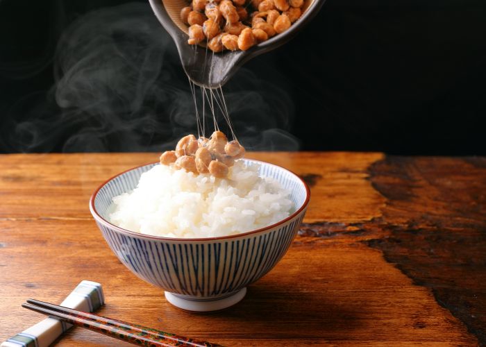 Natto being poured over a bowl of rice.
