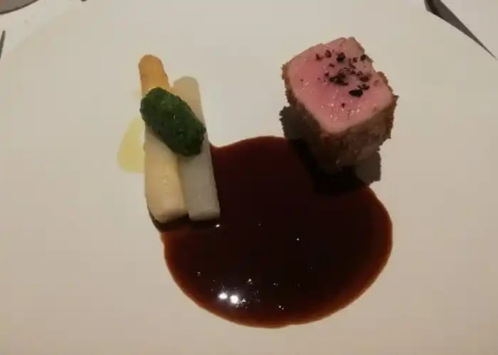 A Michelin star meal at SINAE, featuring meat and vegetables in a rich sauce.