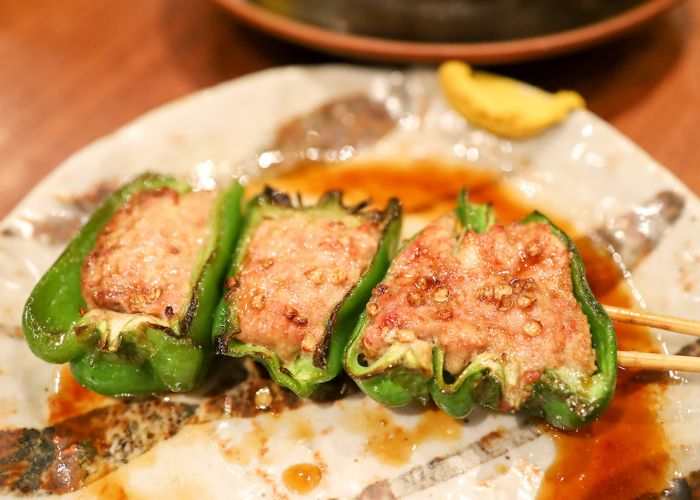 Grilled meat inside a green pepper on a plate, surrounded by meat juice.