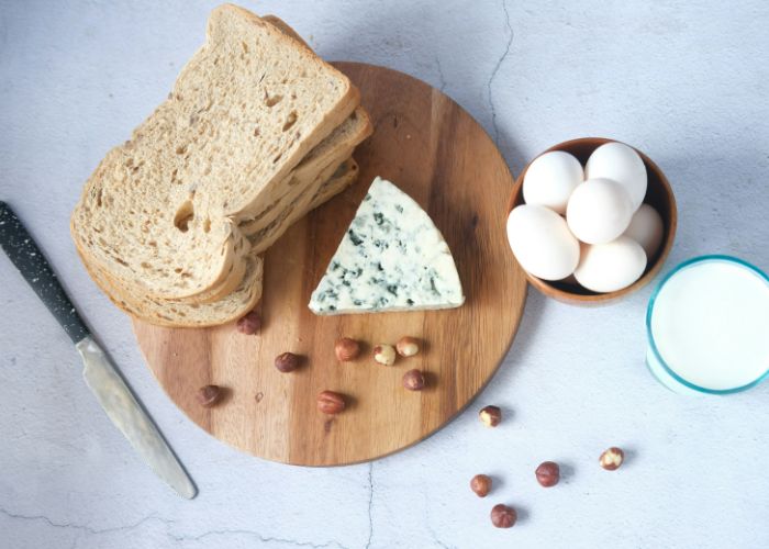 A table covered in common allergens, including wheat bread, cheese, nuts, eggs, and milk.