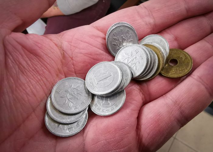A collection of 1 and 5 yen coins in someone's hand.