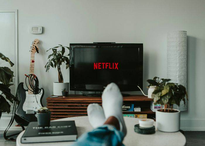 Someone relaxing at home, legs crossed, watching Netflix on the TV.