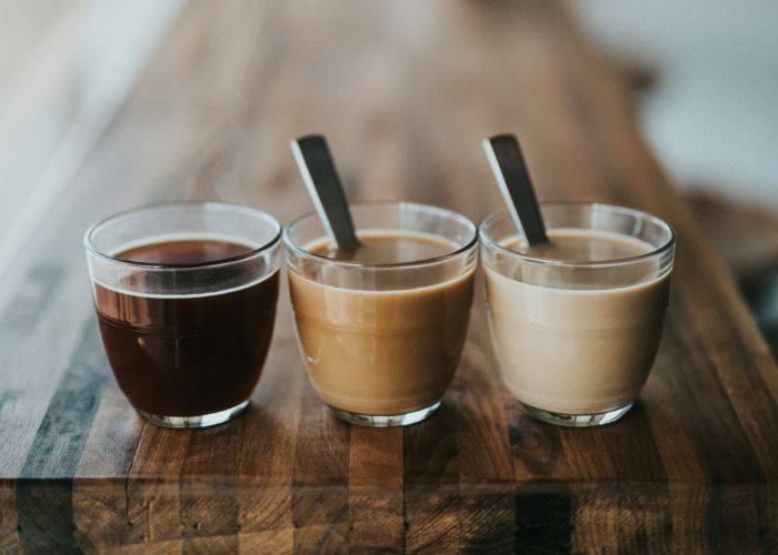 Three coffees in glasses, ranging from black to dark to milky.