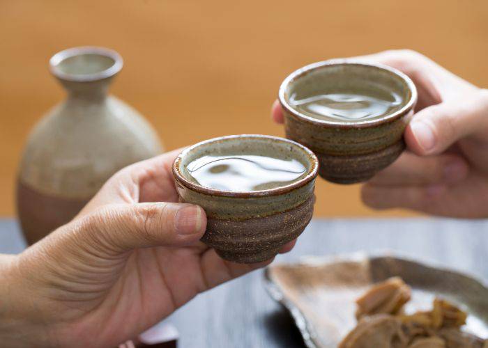 Two raised cups of Japanese sake.