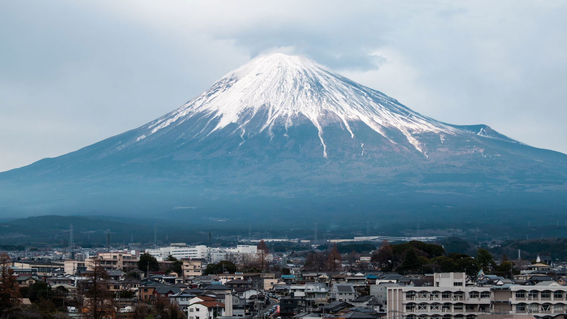 Majestic Mount Fuji towering over the cityscape on a cloudy day