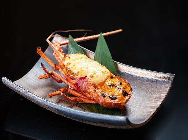 Grilled lobster with cheese on elegant plate with green leaves