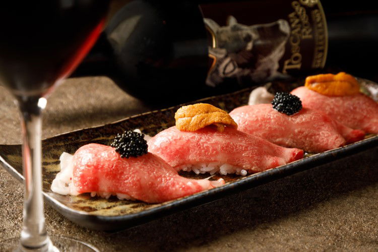 Raw slices of beef draped over rice and garnished with caviar and sea urchin.