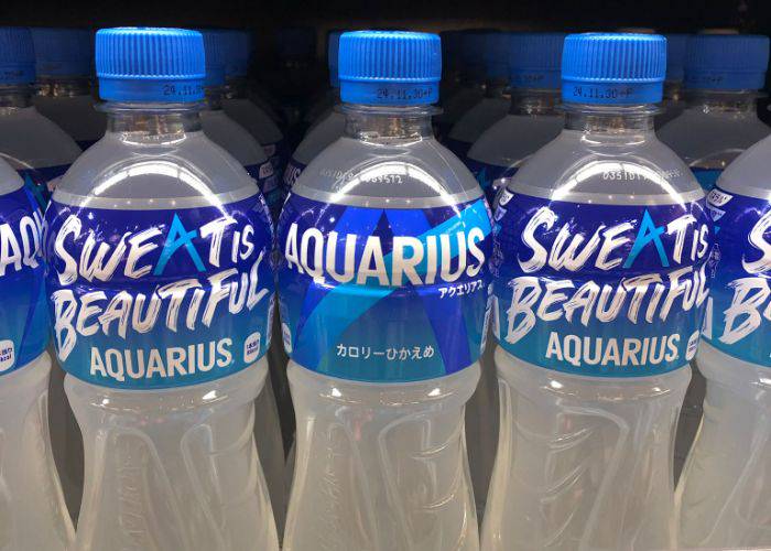 Bottles of Aquarius lined up in a fridge. They say, "Sweat is beautiful" on them.