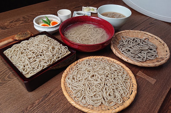 Assorted soba noodles on wooden table with traditional Japanese presentation