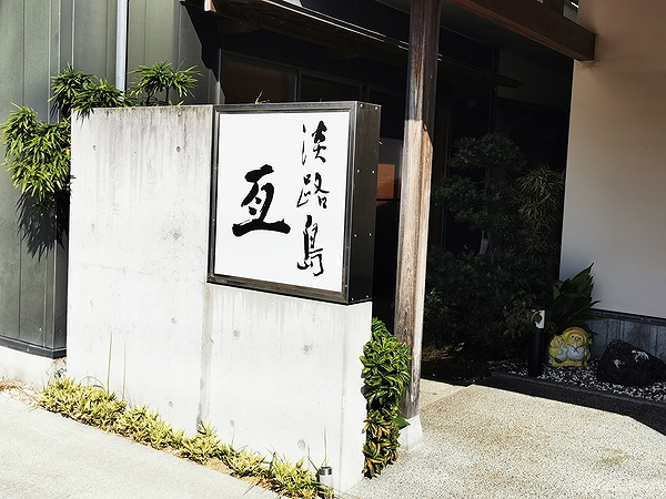Japanese restaurant entrance with stylish sign and greenery