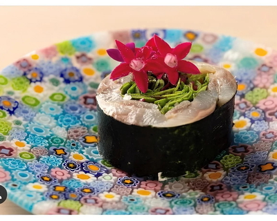 Exquisite sushi roll with vibrant floral garnish on patterned plate