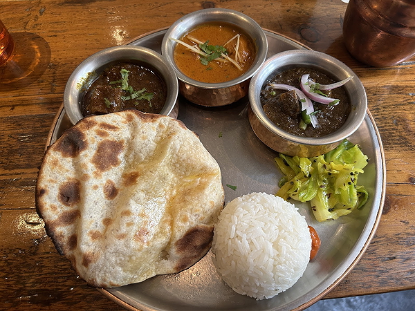 Traditional Indian thali with naan, rice, and curries on restaurant table