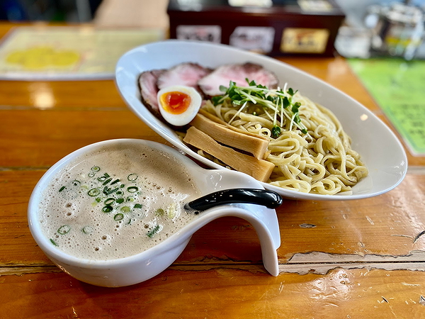 Delicious ramen with pork, egg, and creamy broth on wooden table