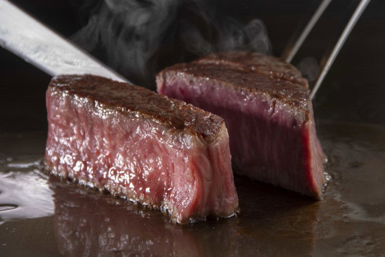 Juicy grilled steak sizzling on a hot pan