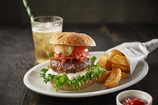 Gourmet burger with lettuce, tomato, and fries at a trendy restaurant