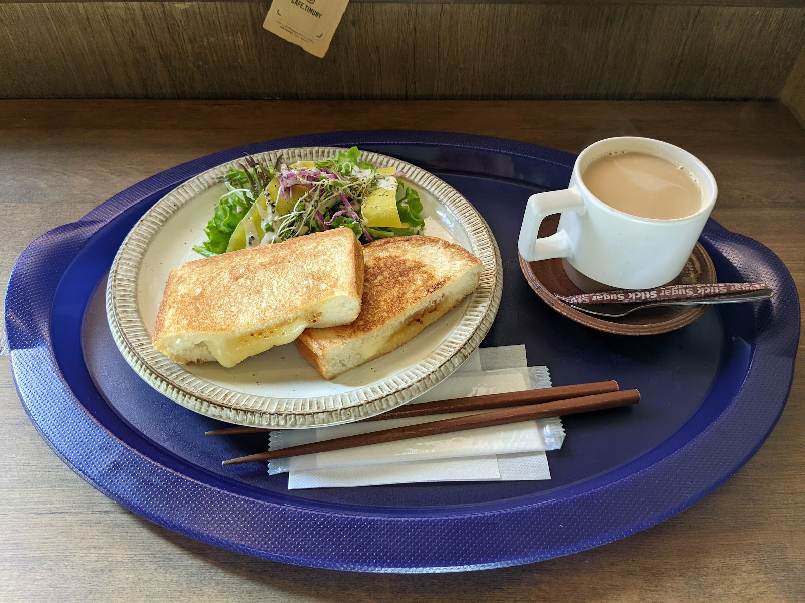 Grilled cheese sandwich with salad and coffee on a blue tray