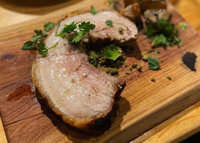 A juicy cut of cooked meat at Falo, resting on a wooden board.