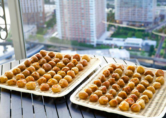 Bamboo trays of umeboshi, pickled plums drying by a window in Japan.