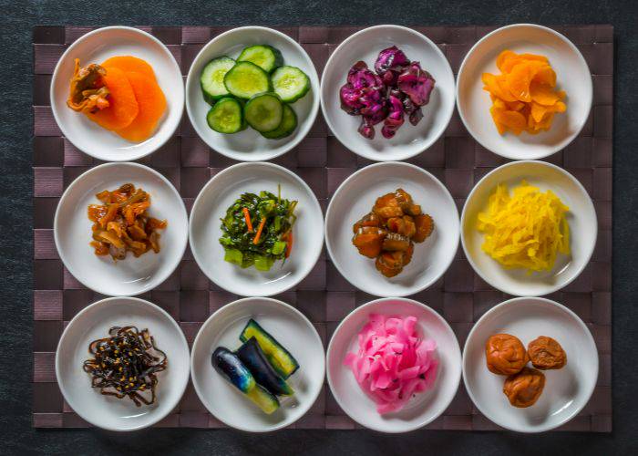 A top-down shot of many different types of pickled vegetables on a checkered mat.