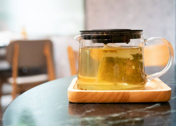A glass tea pot with genmaicha tea bags steeping.