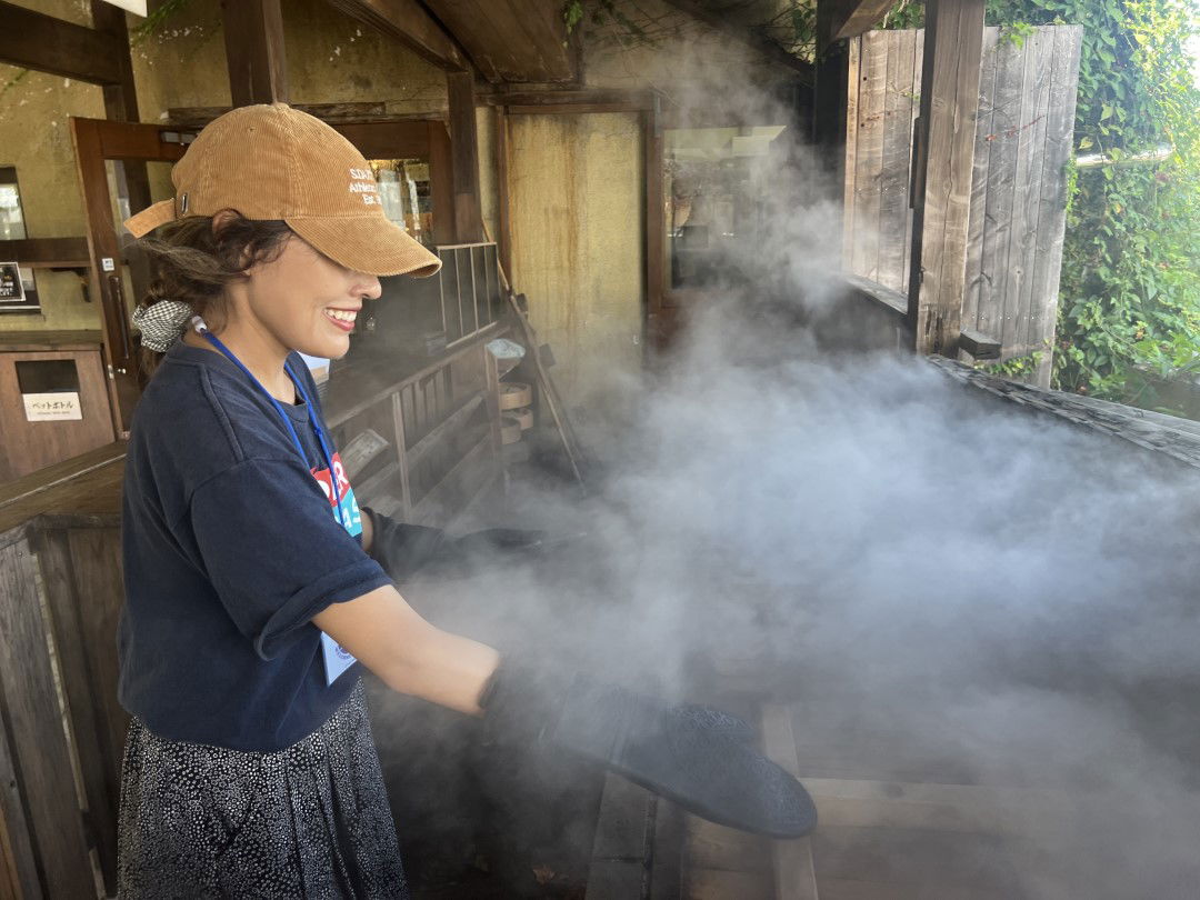 A guest smiling while trying jigokumushi steam cooking in Beppu.