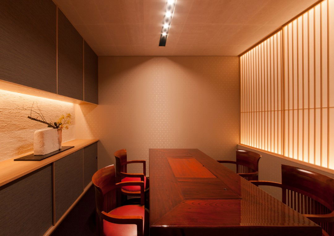 The minimal dining room of Gomangoku Honten, featuring sleek woods and empty surfaces.