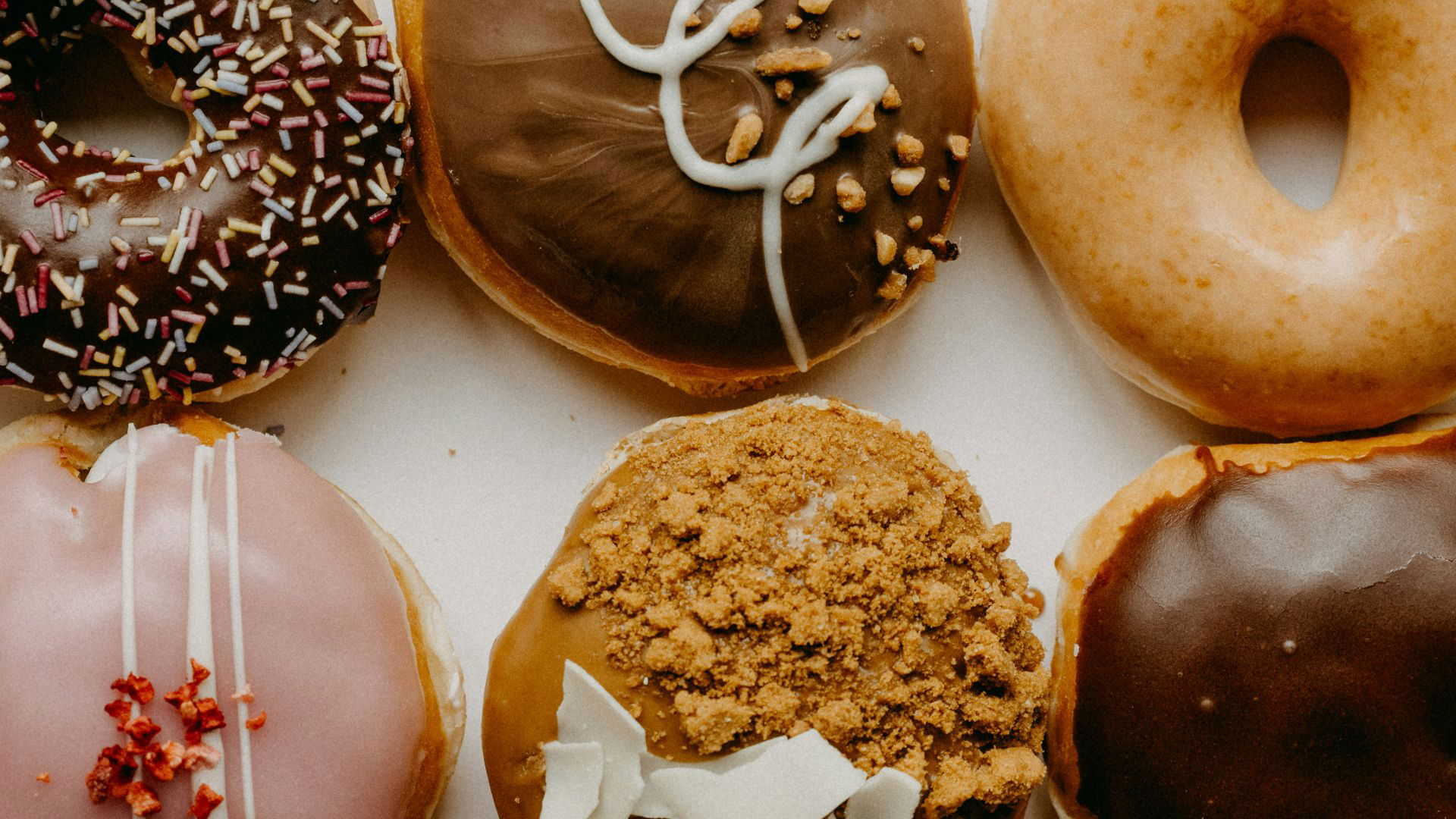Assorted gourmet donuts with sprinkles and glaze on white background