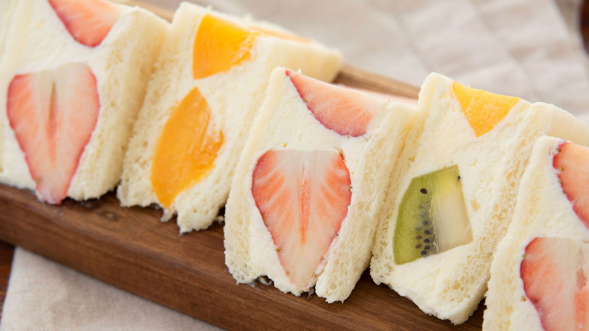 Fresh fruit-filled sandwich slices on a wooden board