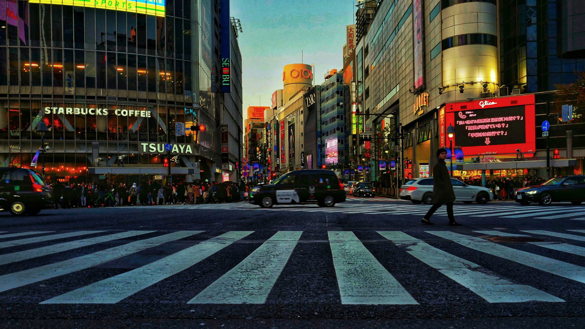 Tokyo Shibuya Crossing at dusk with city lights and people crossing