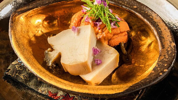 Elegant gourmet dish with uni and decorated tofu on a ceramic plate