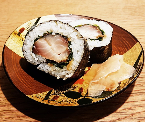 Delicious sushi roll with fresh fish and pickled ginger on a decorative plate