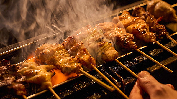 Grilled skewers sizzling over open flames at a restaurant
