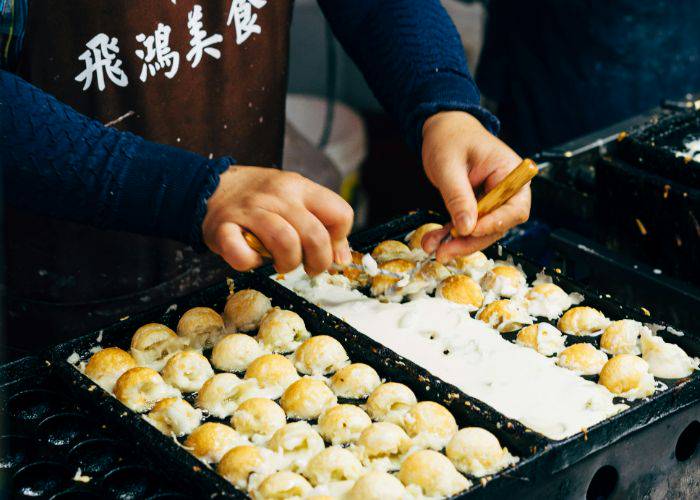 A street food vending in Osaka making takoyaki.