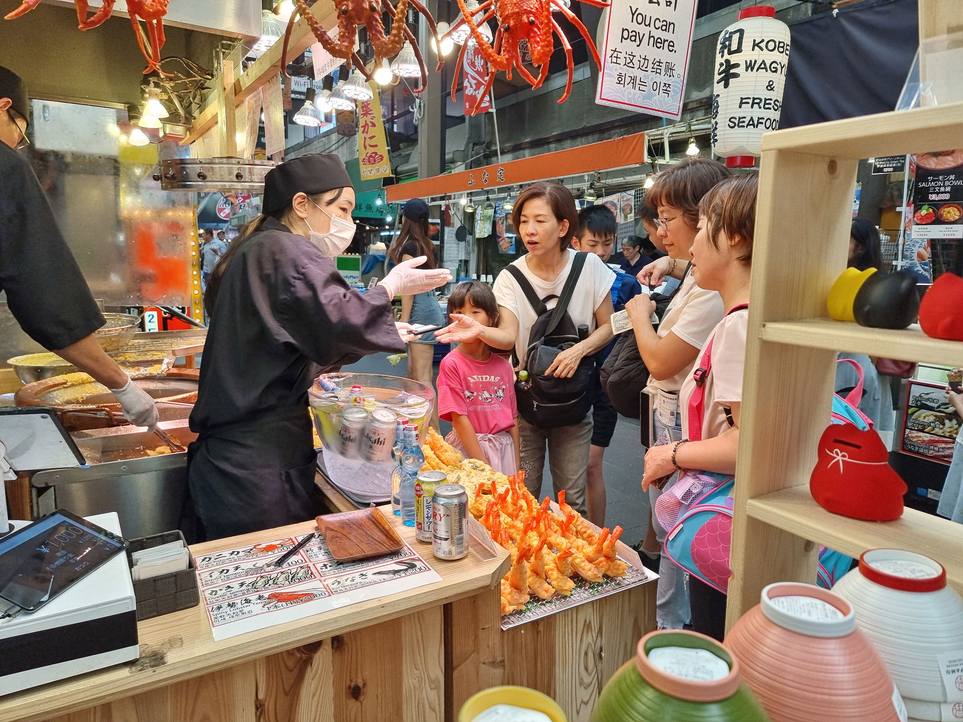 A family talking to a stall worker during a tour of Kuromon Market in Osaka