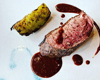Gourmet steak dish with sauce and grilled side