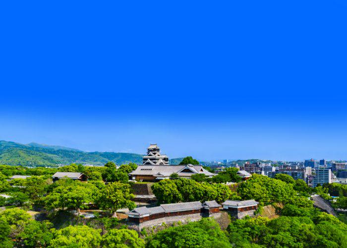 Kumamoto on a sunny day, showing off the Kumamoto Castle amidst green trees.