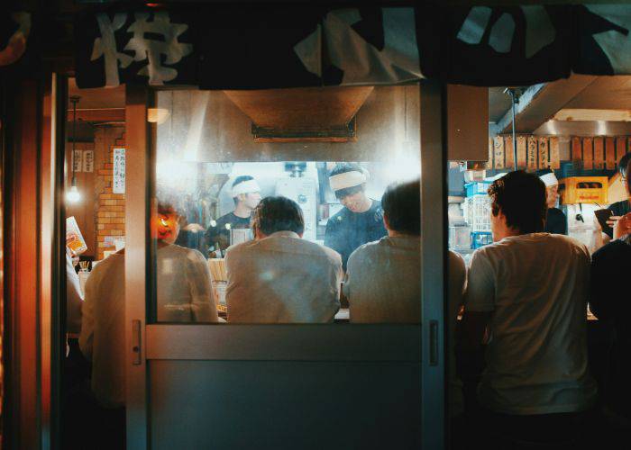 A group of salarymen crowded into a small izakaya bar.