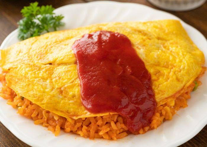 Omurice: A fluffy yellow omelet laid over fried rice and covered in tomato sauce.
