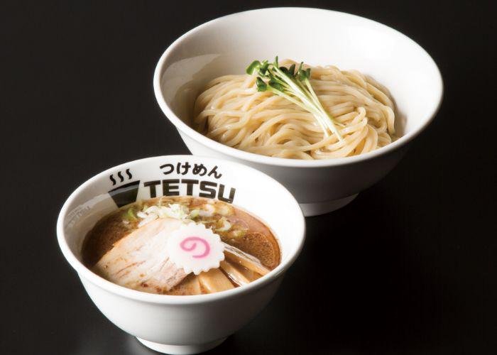 Tsukemen from Tetsu, one of the best ramen shops in Tokyo. One bowl of noodles and one bowl of broth against a dark background.
