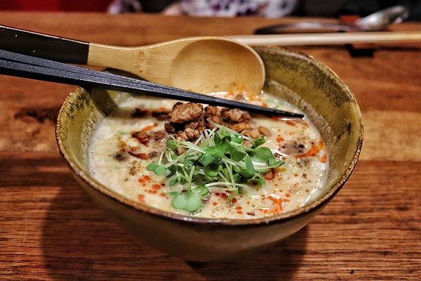 Delicious bowl of ramen with fresh garnish on a wooden table