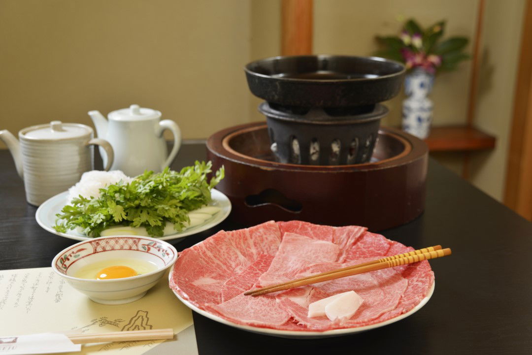 Traditional Japanese course menu with sliced wagyu and hot pot setup