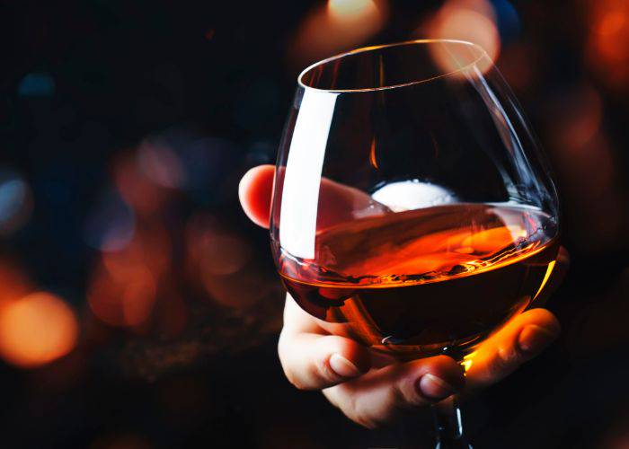 A glass of cognac, held in someone's hand.