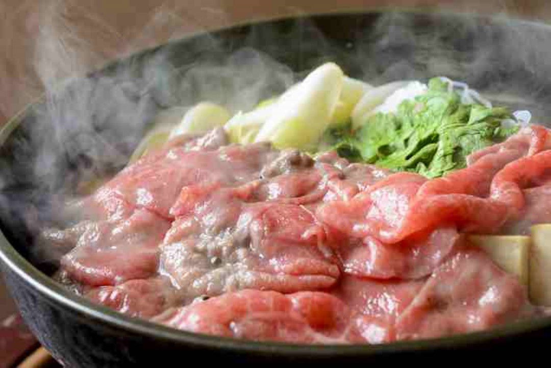 Sizzling beef slices with vegetables in a steaming hot pot