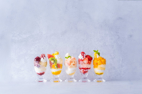 Assorted fruit parfaits in glass cups with light background