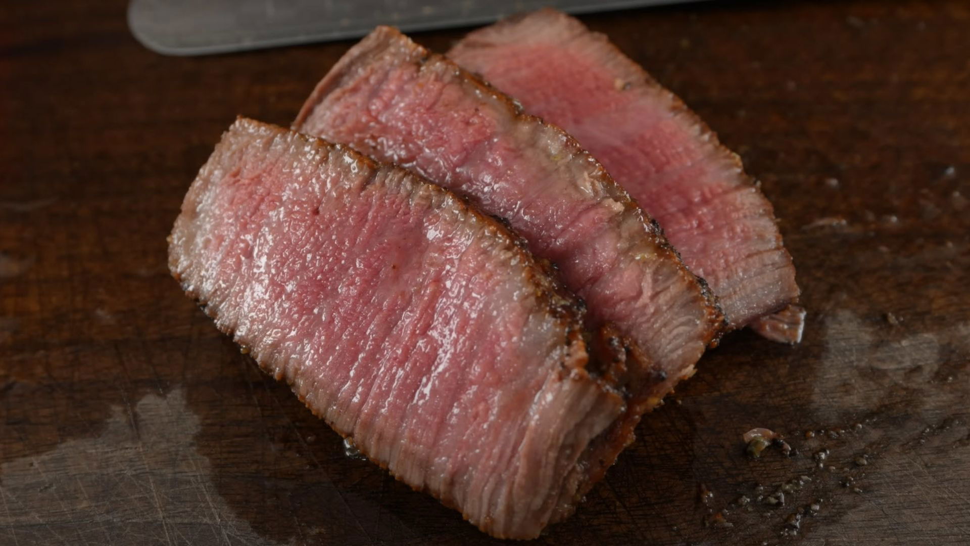 Perfectly cooked medium-rare steak slices on a wooden board