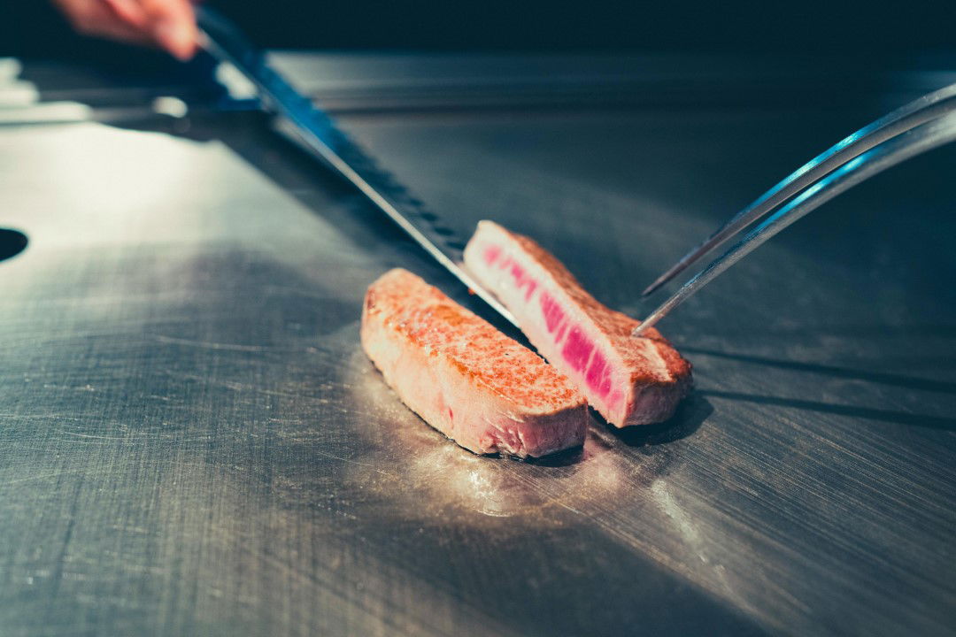 A medium-rare slice of beef being grilled on a teppanyaki grill.