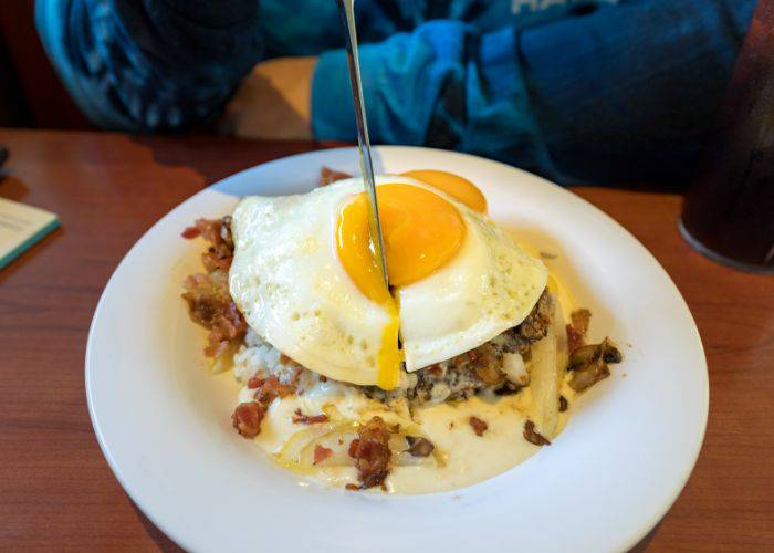 Breakfast platter with someone cutting through an over easy egg